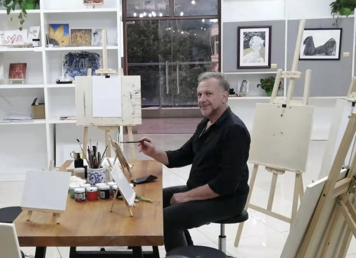Angelo Segarra painting in his art studio, surrounded by easels and artwork
